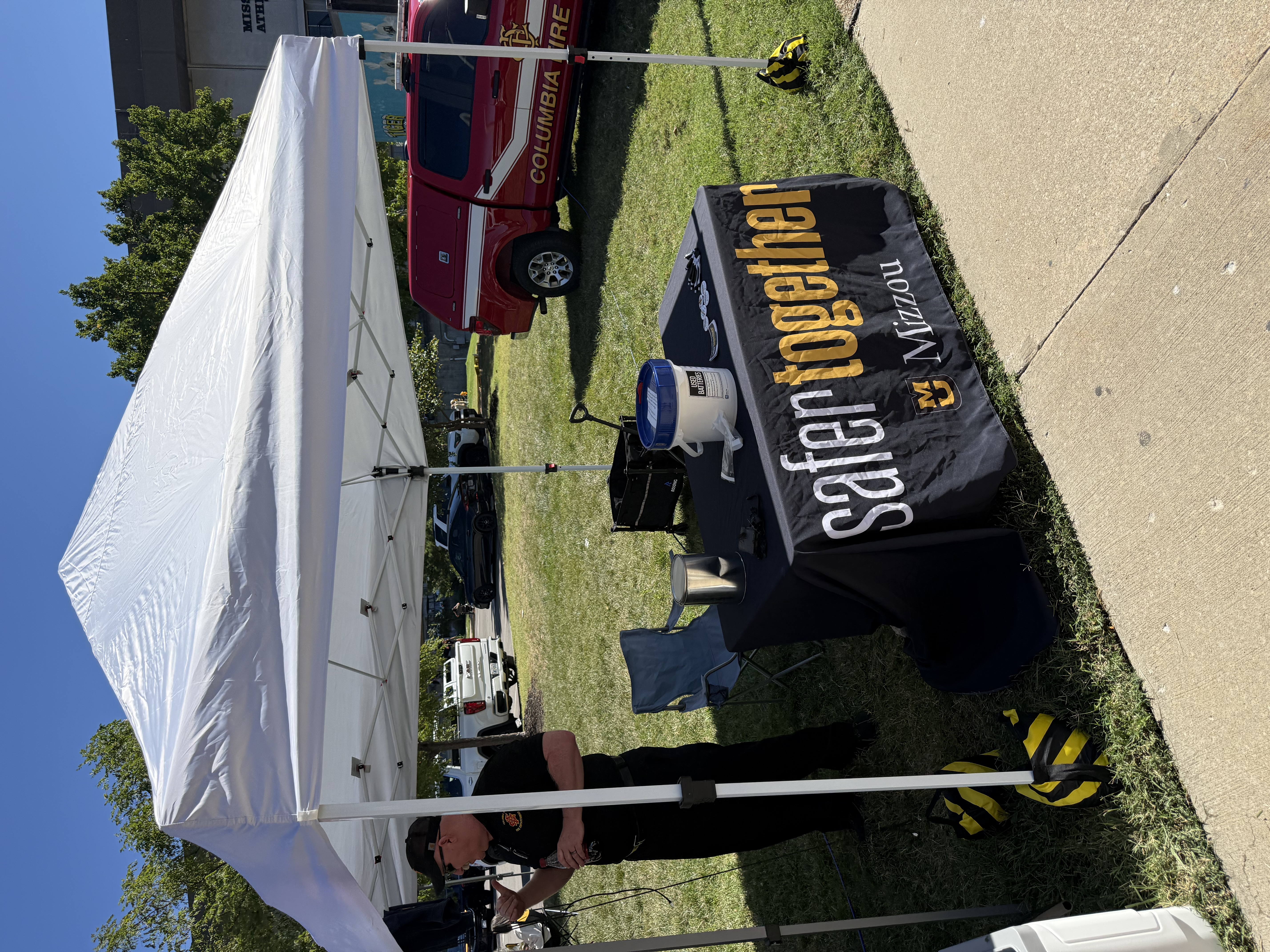 A tent with a table underneath reading safer together